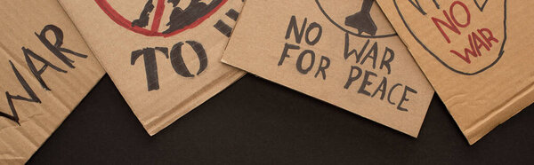 top view of cardboard placards with no war lettering on black background, panoramic shot
