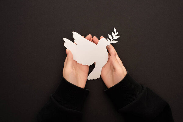 частичный вид женщины, держащей голубя с белой бумагой на черном фоне
