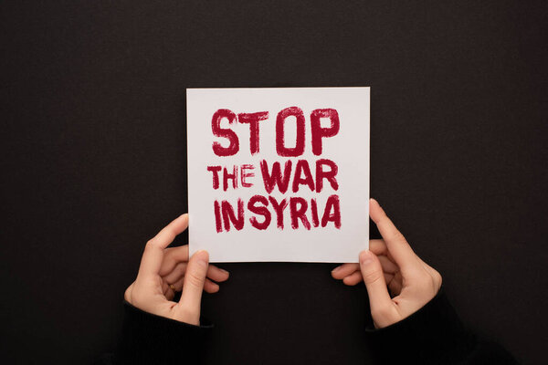 cropped view of woman holding white placard with red stop war in Syria lettering on black background