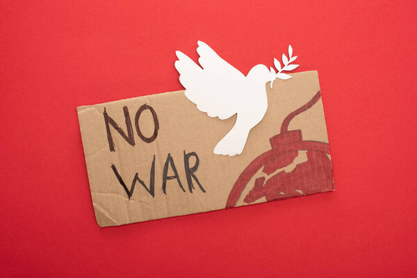top view of cardboard placard with no war lettering and bomb with white paper dove on red background