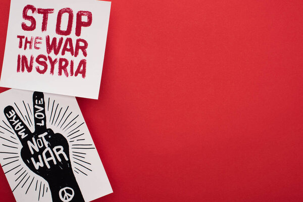 top view of drawings with make love not war and stop war in Syria lettering on red background