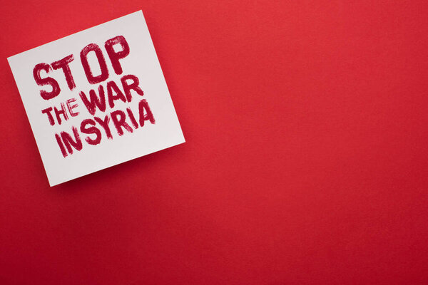 top view of white placard with stop war in Syria lettering on red background