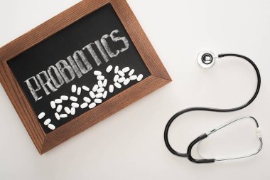 Probiyotik harfli karatahtanın beyaz arkaplanda haplar ve steteskopla üst görünümü