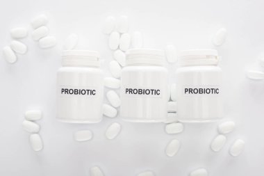 top view of containers with probiotic lettering near pills on white background clipart