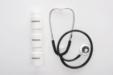 top view of containers with probiotic lettering near stethoscope on white background clipart