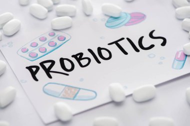 selective focus of drawing with probiotics lettering near pills on white background clipart