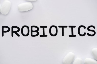 top view of paper with probiotics lettering and pills on white background clipart