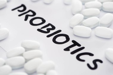 Probiyotik harfleri ve beyaz arka planda hapları olan seçici kağıt odağı