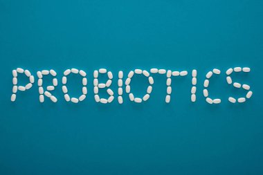 top view of probiotics lettering made of pills on blue background clipart