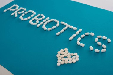probiotics lettering and heart made of pills on blue and white background clipart