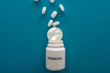 top view of white probiotic container with pills on blue background clipart