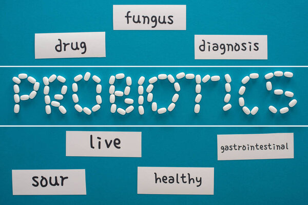 top view of probiotics lettering made of pills near paper cards with words on blue background