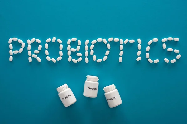 top view of probiotics lettering made of pills and containers on blue background