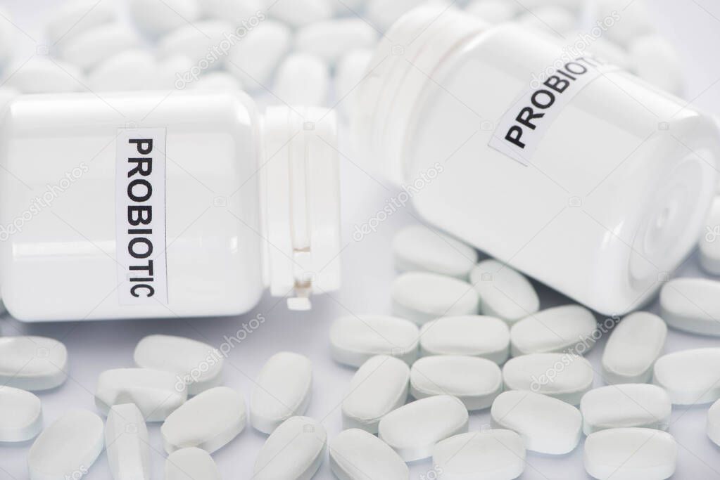 selective focus of probiotic containers and pills on white background