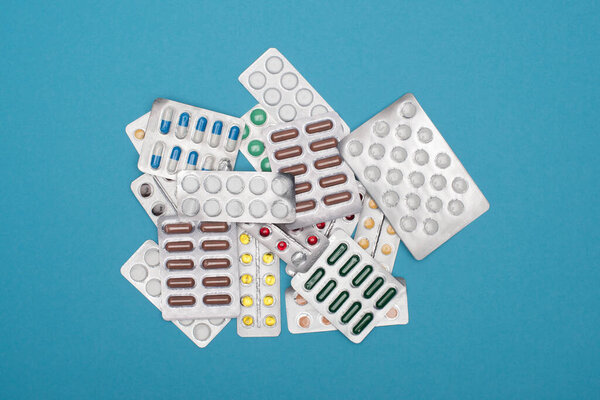top view of colorful pills in blister packs on blue background