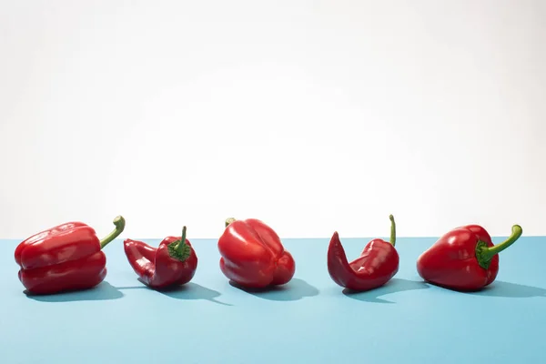 Φρέσκες Κόκκινες Πιπεριές Και Τσίλι Μπλε Επιφάνεια Λευκό Φόντο — Φωτογραφία Αρχείου