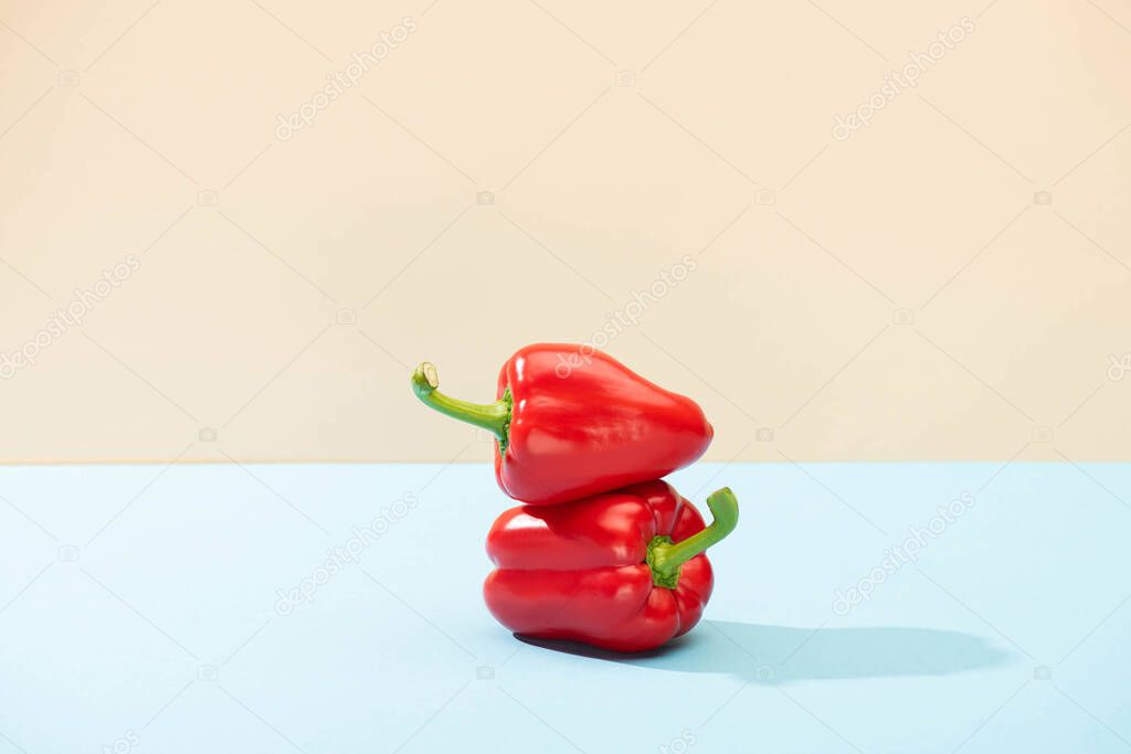 Fresh red bell peppers on blue surface isolated on beige