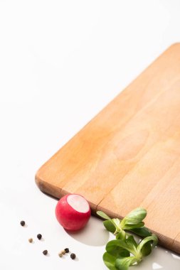 delicious radish and greens with black pepper near wooden board on white background clipart