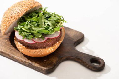 Lezzetli vejetaryen burger, turp ve beyaz arka planda ahşap tahta roka.