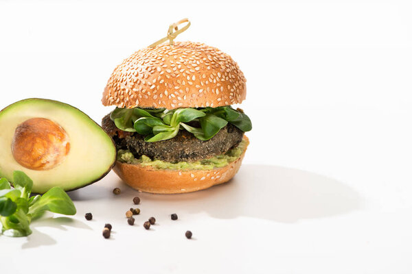 delicious green vegan burger with microgreens, avocado, black pepper on white background