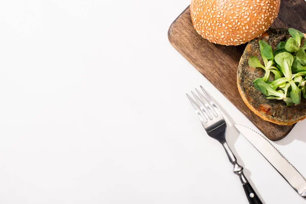 在白色背景的餐具旁边的木板上有微绿色素食汉堡的顶部视图 — 图库照片