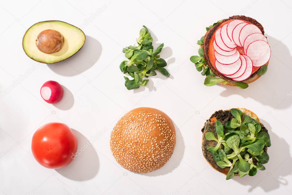 top view of vegan burgers with vegetable ingredients on white background