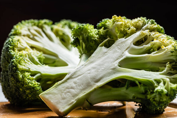 close up view of fresh green cut broccoli on wooden cutting board isolated on black