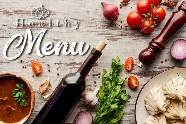 Top view of delicious khinkali near bottle of wine, kharcho, vegetables and spices on wooden table, healthy menu illustration — Stock Image Top View Delicious Khinkali Bottle Wine Kharcho Vegetables Spices Wooden Stock Photo