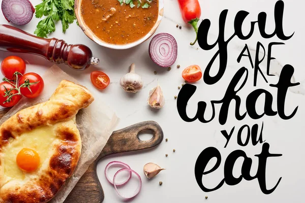 Top view of adjarian khachapuri, soup kharcho, vegetables and spices on marble texture, you are what you eat illustration — Stock Image Top View Adjarian Khachapuri Soup Kharcho Vegetables Spices Marble Texture Stock Image