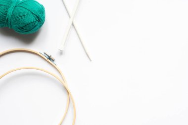 top view of green wool yarn, knitting looms and knitting needles on white background clipart