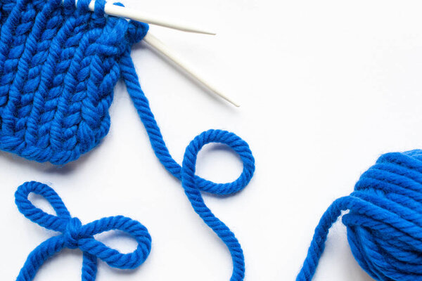 blue wool yarn and knitting needles on white background