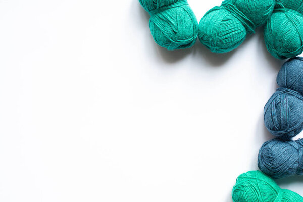 top view of blue and green wool yarn on white background with copy space