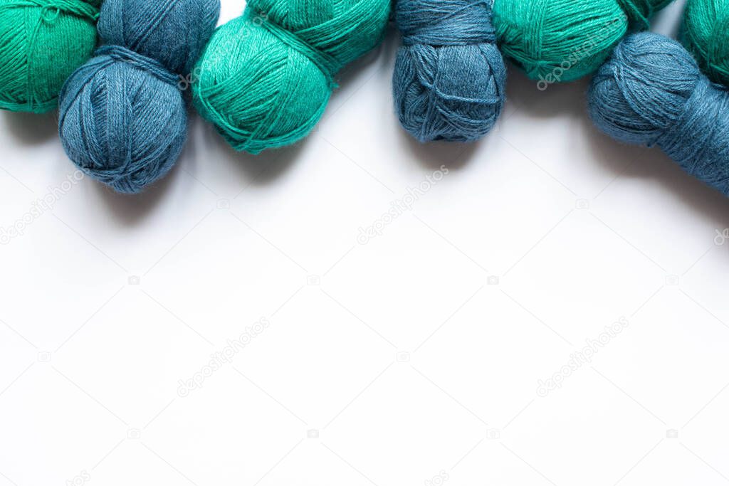 top view of blue and green wool yarn on white background with copy space
