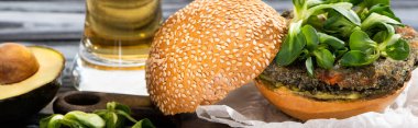 Kesme tahtasında, panoramik mahsulde servis edilen mikroyeşillikli ve avokadolu lezzetli vejetaryen burger.