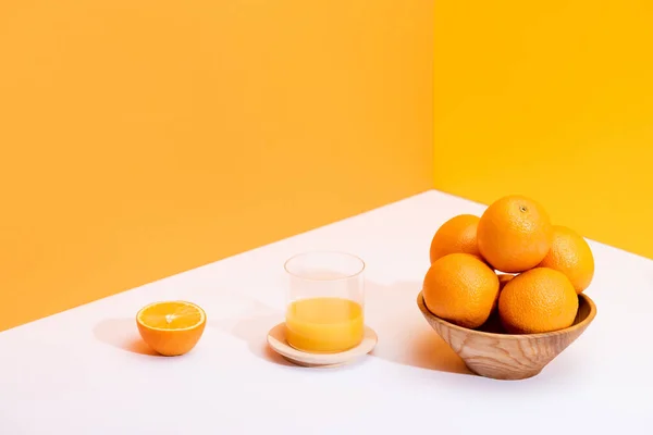 Świeży Sok Pomarańczowy Szkle Pobliżu Dojrzałych Pomarańczy Misce Białej Powierzchni — Zdjęcie stockowe