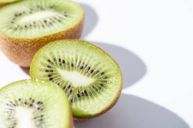 selective focus of green kiwifruit halves on white  clipart