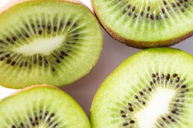 top view of green and ripe kiwifruit halves on white  clipart