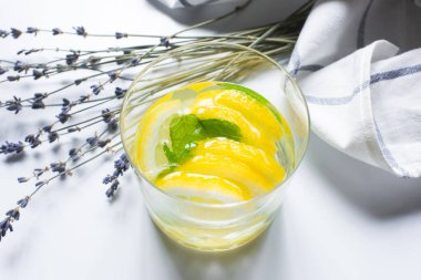 Bardakta taze zencefilli limonata, lavantanın yanında nane ve beyaz arka planda peçete.