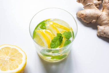 Limonun yanında taze limonata ve beyaz arka planda zencefil kökü.