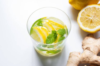 Limonun yanında taze limonata ve beyaz arka planda zencefil kökü.