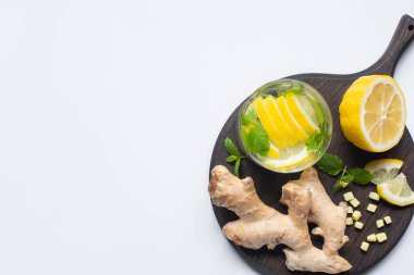 Limonların yanında taze limonata ve beyaz arka planda siyah tahta üzerinde zencefil kökü.