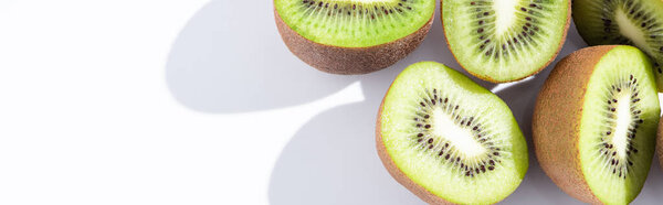 panoramic crop of fresh and ripe kiwifruit halves on white 