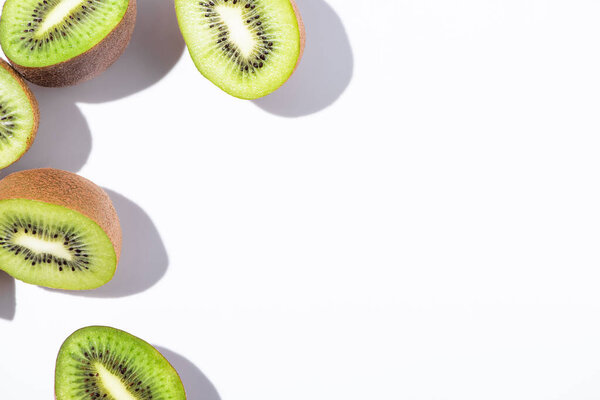 top view of ripe and green kiwi fruit halves on white 
