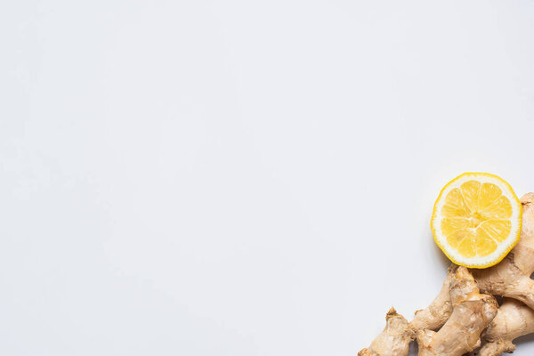 вид сверху на свежий лимон и корень имбиря на белом фоне
