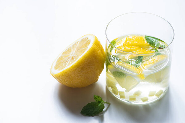 свежий имбирный лимонад в стакане с лимоном и мятой на белом фоне
