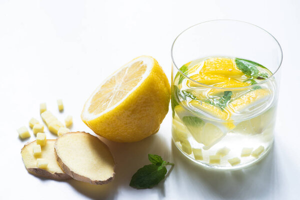 fresh ginger lemonade in glass with lemon and mint on white background