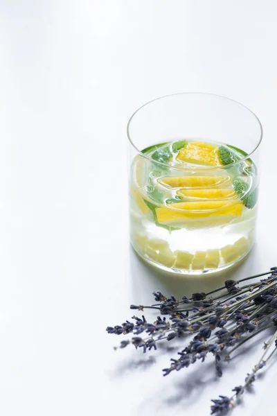 fresh lemonade in glass with lemon and ginger near lavender on white background