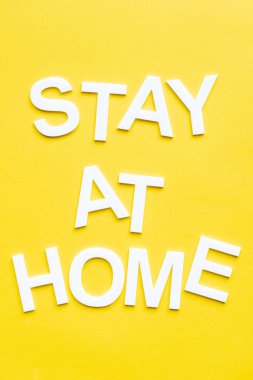 Top view of stay at home white lettering on yellow background clipart