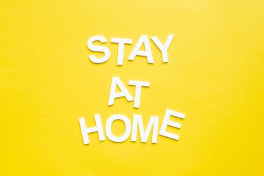 Top view of stay at home lettering on yellow surface clipart