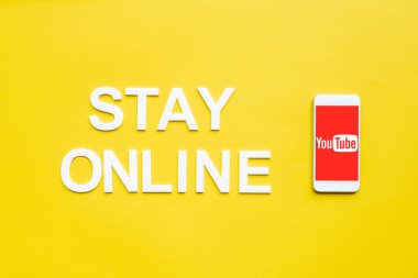 KYIV, UKRAINE - 8 Nisan 2020: Sarı yüzey üzerinde youtube uygulaması olan çevrimiçi harf ve akıllı telefonun üst görünümü